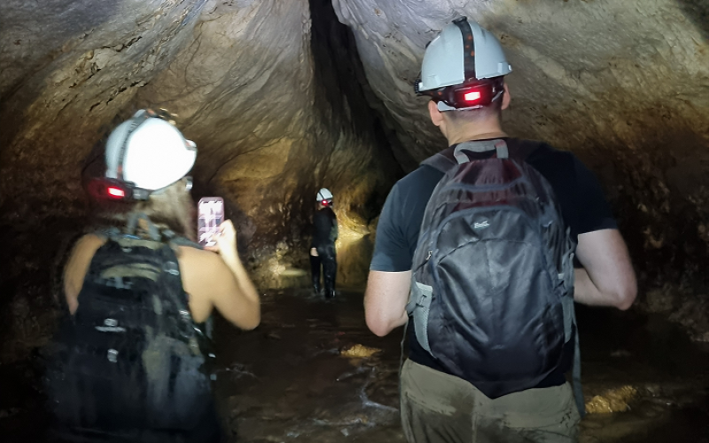 Tres turistas tomando fotos al interior de una caverna